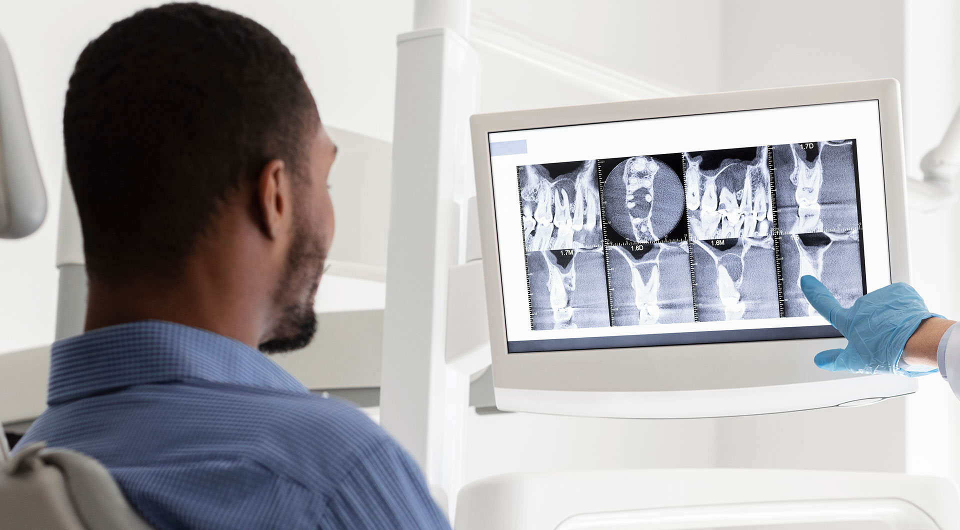 The image shows a person sitting at a computer screen with medical images displayed on it, while another individual appears to be observing the screen from behind.