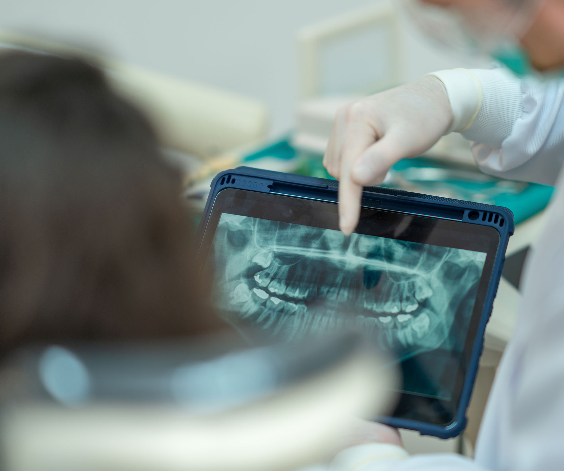 An orthodontist using a tablet to review an X-ray of a patient s teeth.